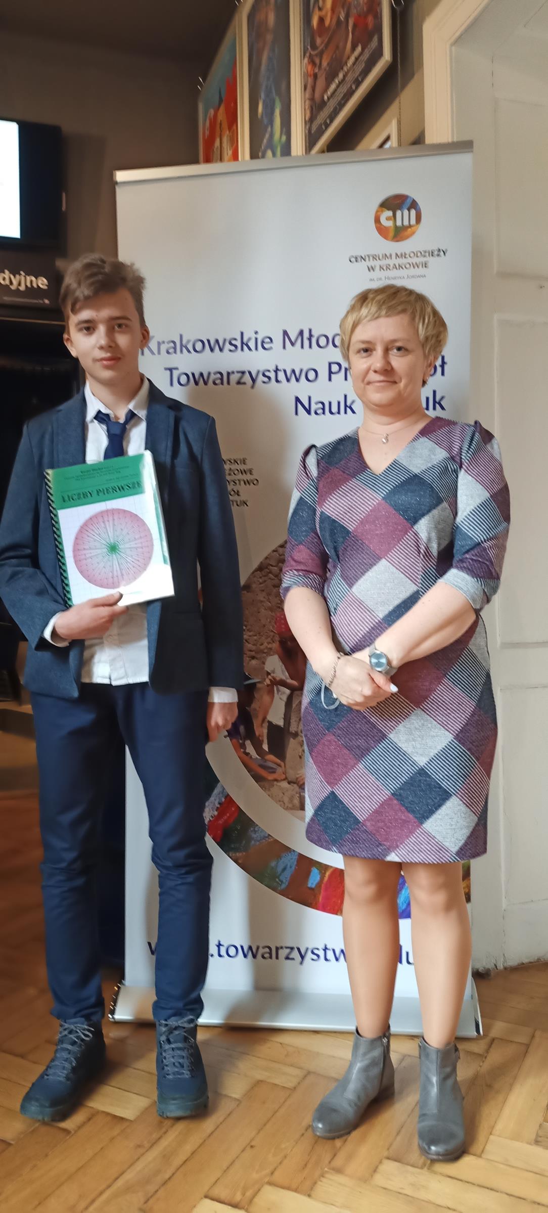 Fotografia przedstawia ucznia klasy 1A, który zdobył nagrodę drugiego stopnia w konkursie Małopolskich Prac Matematycznych wraz z opiekunem